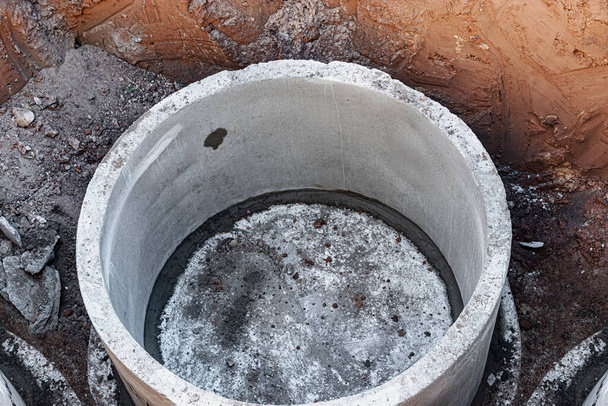 Montáž betonových studní v zemi na staveništi. Použití železobetonových kroužků pro žumpy, přetečení septických nádrží. Zlepšení studní a kanalizace - Fotografie, Obrázek