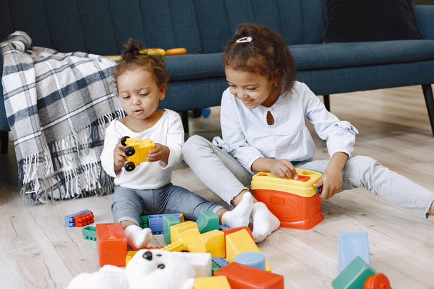 Cute little girls playing with toys on the floor near the couch - Photo, image