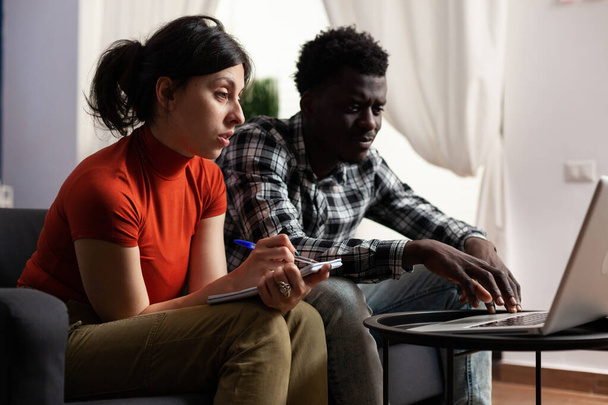 Couple Interracial calculant l'argent des impôts à l'aide d'un ordinateur portable - Photo, image