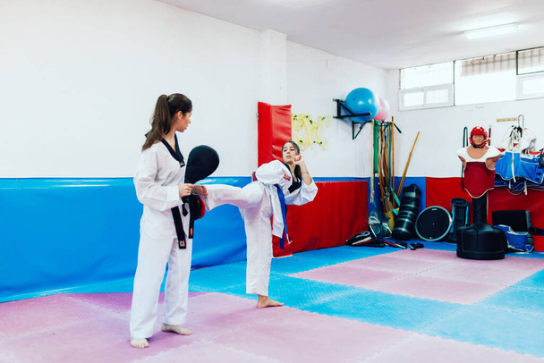 Two young women practice taekwondo in a training center - Photo, Image