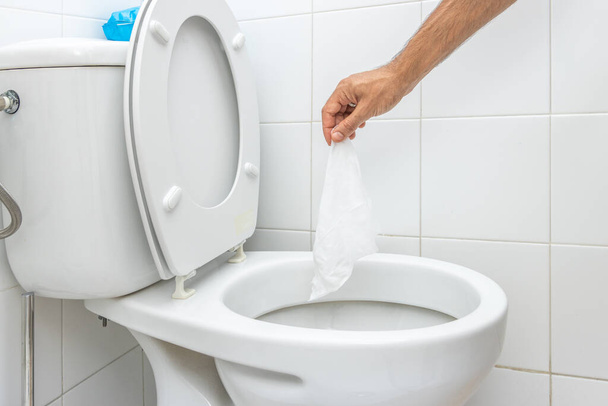 Hand throwing wet wipe into toilet - Zdjęcie, obraz