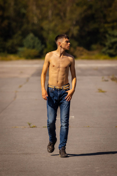 An eighteen year old teenage boy walking on a warm summer's day while in jeans and shirtless - Valokuva, kuva