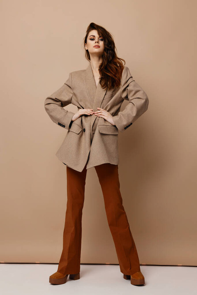 confident woman model coat trousers and boots holds hands at the waist - Foto, immagini