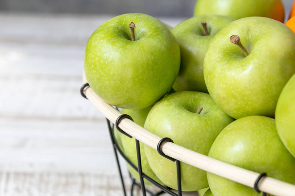 panier avec pommes vertes sur une table en bois clair close-up, concept d'alimentation saine et de régime alimentaire, place pour le texte - Photo, image