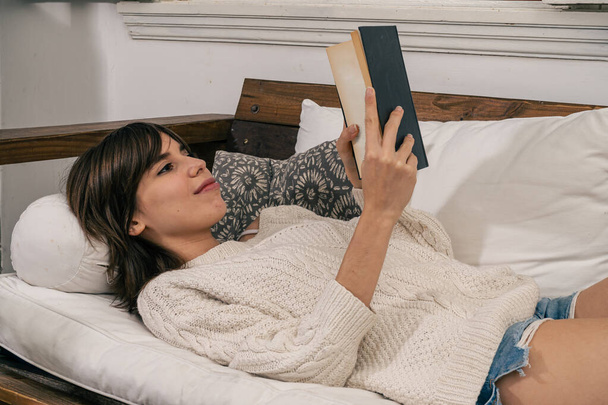 Gelukkig jong vrouw lezen sprookjesboek op bank thuis - Foto, afbeelding