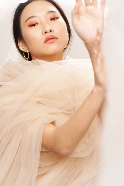 asian woman with transparent fabric on her shoulders gesturing with hands makeup - Foto, imagen