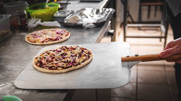 Primer plano de la mano del chef panadero haciendo pizza en la cocina. Poner en la pala de aterrizaje y enviarlo al horno. - Foto, imagen