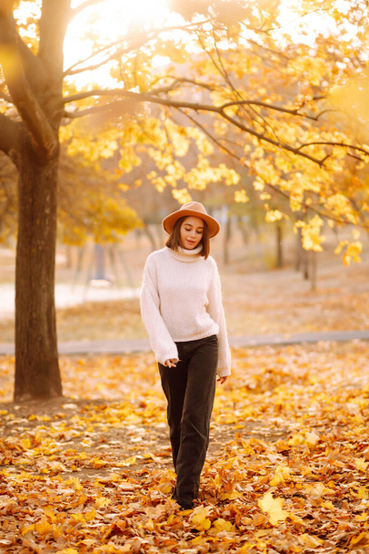 Sunny lifestyle portrait of young stylish woman walking on park, wearing cute trendy hat. Fashion, style concept. People, relaxation and vacations concept. - Photo, image