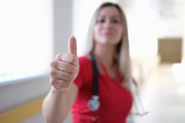 Femme médecin en uniforme rouge montrant pouce vers le haut gros plan - Photo, image