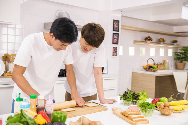 Азійські геї молотять пшеничний хліб, щоб приготувати бутерброд і салат на кухні. Щасливого молодого ЛГБТ життя вдома. Гомосексуальна сім "я з здоровим харчуванням вранці після пробудження. - Фото, зображення