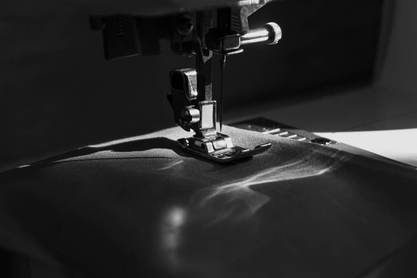 máquina de coser vista de cerca con la luz natural del sol, la moda lenta y el concepto de costura en el hogar en blanco y negro - Foto, imagen