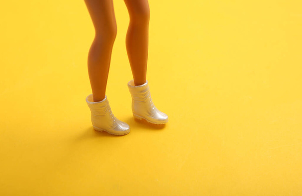 Doll female legs in boots on yellow background. Creative minimalistic layout - Fotografie, Obrázek
