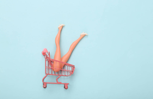 Doll feet in a shopping cart. Minimalism, concept art - Foto, Imagen