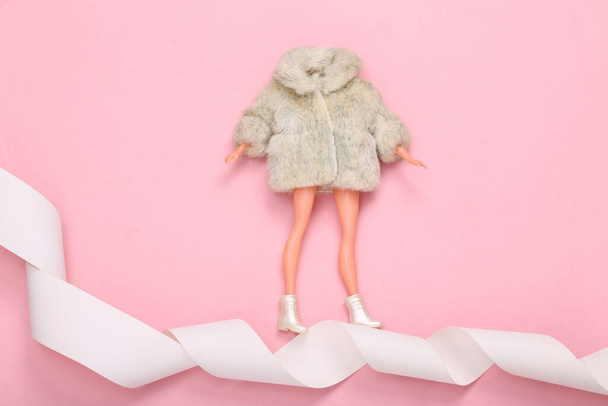 Woman Doll in fur coat on payment tape. Minimalism shopping concept. Top view. Flat lay - Фото, изображение