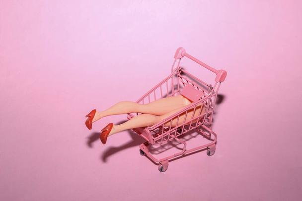 Minimalistic layout with doll legs in shopping trolley. Concept art - Fotoğraf, Görsel