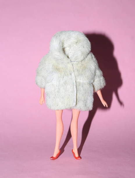 Κούκλα κούκλα σε ζεστή γούνα σε ροζ φωτεινό φόντο. Μινιμαλιστικό πλάνο μόδας. Έννοια τέχνης - Φωτογραφία, εικόνα