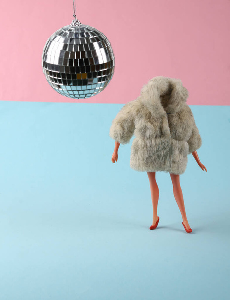 Doll in fur coat and disco ball on a blue pink background. Party. Concept art - Фото, изображение