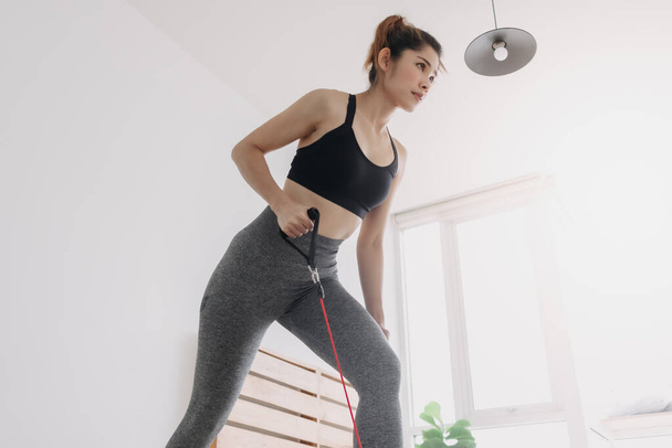 Woman do Resistance Band Crank the Mower workout in her bedroom. - Φωτογραφία, εικόνα