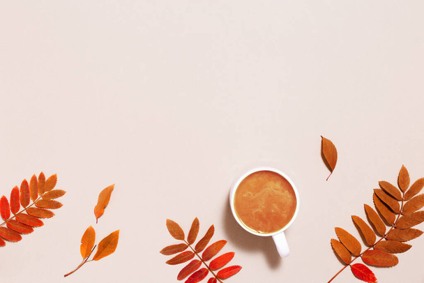Cup of coffee with milk and red autumn leaves on pastel pink paper background. Autumn, fall composition, monohrome flat lay, top view, copy space. - Foto, imagen
