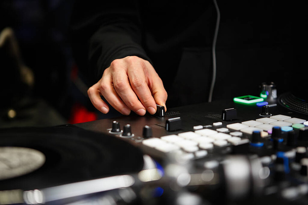 Disc jockey mixes music with cross fader knob on sound mixer device. Professional hip hop dj playing musical tracks on party with turntables and modern mixing controller - 写真・画像