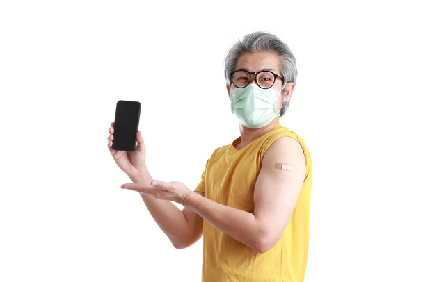 O homem asiático sênior com máscara mostrando gesso em seu ombro. - Foto, Imagem