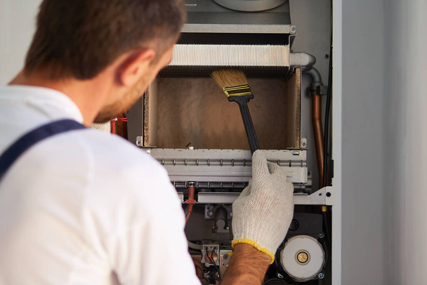 Limpieza del intercambiador de calor del radiador en el calentador de gas. - Foto, Imagen