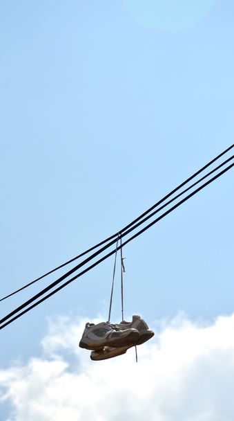 tenisky visící z elektrického drátu proti modré obloze - Fotografie, Obrázek