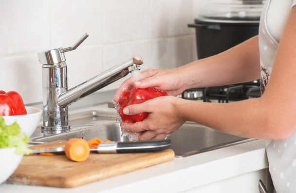 женщина моет овощи красный перец под краном
 - Фото, изображение