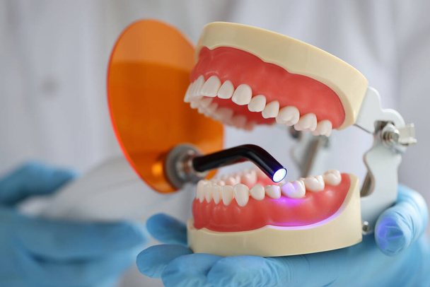 Γιατρός κατέχει γνάθου και οδοντιατρική λάμπα UV για να γεμίσει οδοντιατρική γνάθο - Φωτογραφία, εικόνα