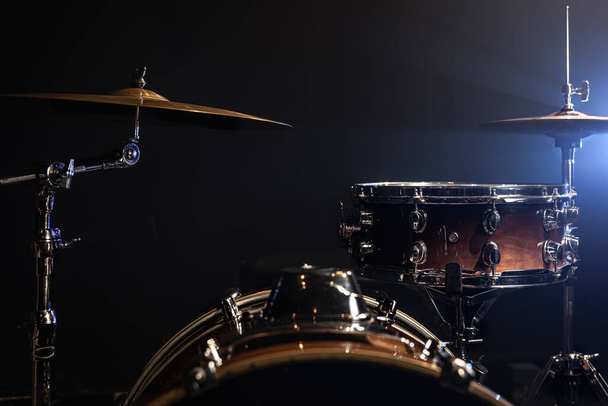 Drums, bass drum, hi-hat, cymbals on a dark background with beams from a spotlight, copy space. - Photo, Image
