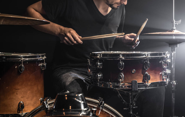 Ein Musiker spielt Schlagzeug mit Stöcken auf der Bühne mit Bühnenbeleuchtung. - Foto, Bild