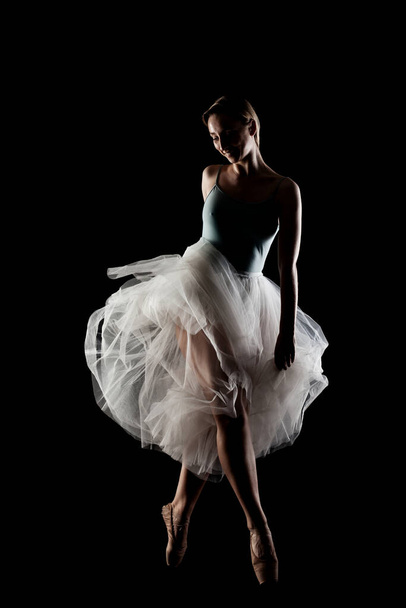 ballerina with a white dress and black top posing on black background - Фото, зображення