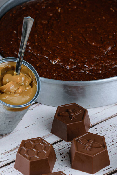 Petits moules au chocolat pour faire du gâteau au miel brésilien, à côté d'une boîte de dulce de leche (photo verticale). - Photo, image