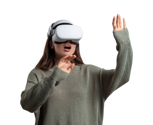 Young attractive businesswoman wearing green sweater and vr helmet is standing and touching air. Concept of modern technology and virtual reality. Isolated over white background - Photo, Image