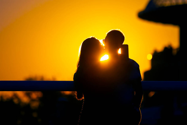 Silhouette of two people in love against the backdrop of the setting sun. Romance in relationships and nature - Foto, Imagem