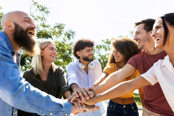Group of united multiracial people stacking hands together - Multiethnic young college students celebrating together on campus university - Foto, Bild