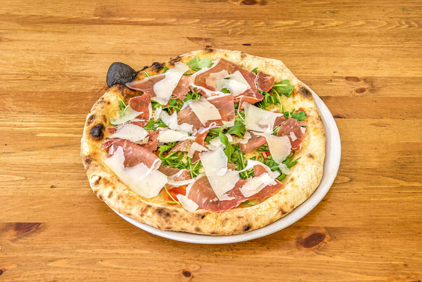 Italiaanse Arugula Pizza met Noten, Parmezaanse Kaasschijfjes en Prosciutto met Tomaat en Mozzarella - Foto, afbeelding