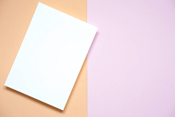 top view of vertical blank white paper card placed on light purple paper and old rose color paper background, flat lay. - Photo, Image