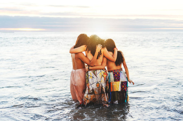 άγνωστες τρεις Λατίνες νέες γυναίκες στον ωκεανό αγκαλιάζονται, μοιράζονται την αγάπη, πίσω όψη - Φωτογραφία, εικόνα