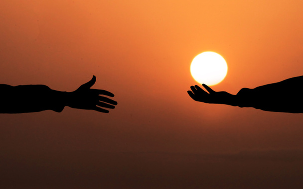 Lidská ruka drží Slunce a dává ho jiné osobě. Pomocná ruka Koncept. Pozadí zapadajícího slunce. Boží koncepce spásy a lehkosti - Fotografie, Obrázek