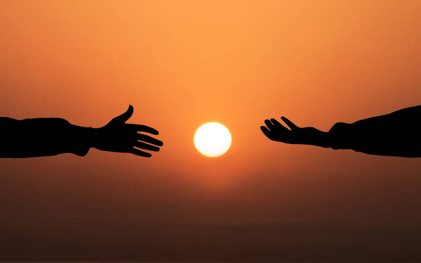 Menselijke hand vragen om hulp Concept. handen elkaar helpen tegen zonsondergang achtergrond. Mensen helpen, God heil en Get Hired Concepts - Foto, afbeelding