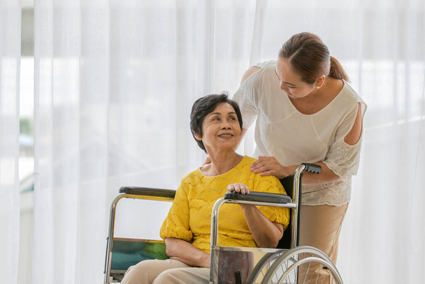 Azji w średnim wieku kobieta wziąć Carre i pomóc starszemu pacjentowi famale na wózku inwalidzkim z uśmiechem szczęśliwy twarz. - Zdjęcie, obraz