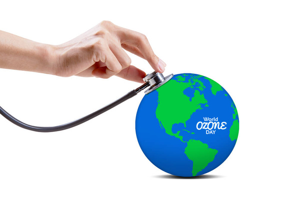 Doctor hand using a stethoscope while examining an earth globe with world ozone day text. Isolated on white background - 写真・画像