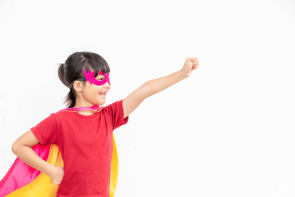 Grappig klein meisje spelen macht superheld over witte achtergrond. superheldenconcept. - Foto, afbeelding