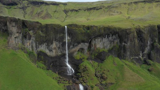Vista aérea sobre la gran cascada en Islandiadrone disparo de montañas verdes y grandes cascadas, septiembre 2021 - Foto, imagen