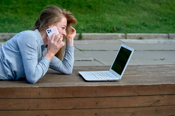 Žena s notebookem sedí na dřevěné plošině, pracuje online - Fotografie, Obrázek