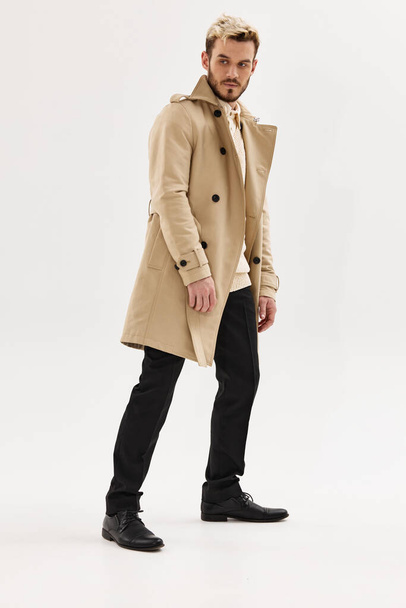 férfi divatos frizura bézs kabát oldalsó pillantás elszigetelt háttér - Fotó, kép