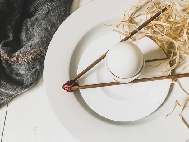 Gekookt ei op een wit bord met houten stokjes - Foto, afbeelding