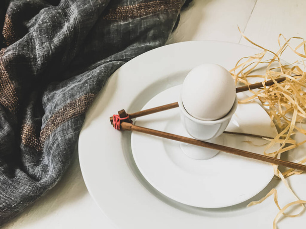 Huevo cocido en un plato blanco con palos de madera - Foto, imagen