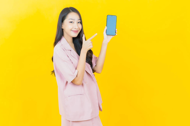 Portrait beautiful young asian woman smile with smart mobile phone on color background - Фото, изображение